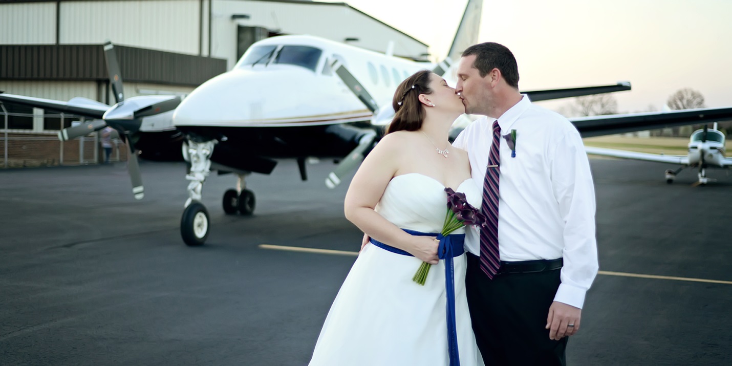 Newly married couple kiss in front of a King Air