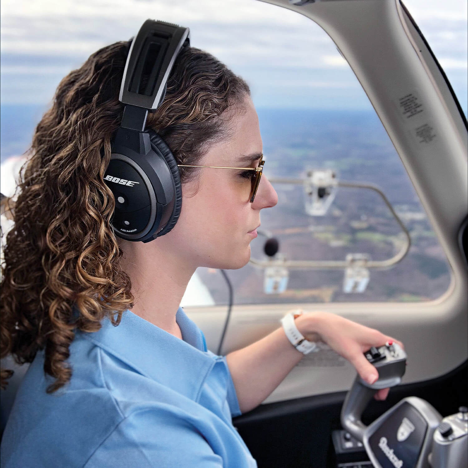Pilot with headset flying a Beechcraft piston.