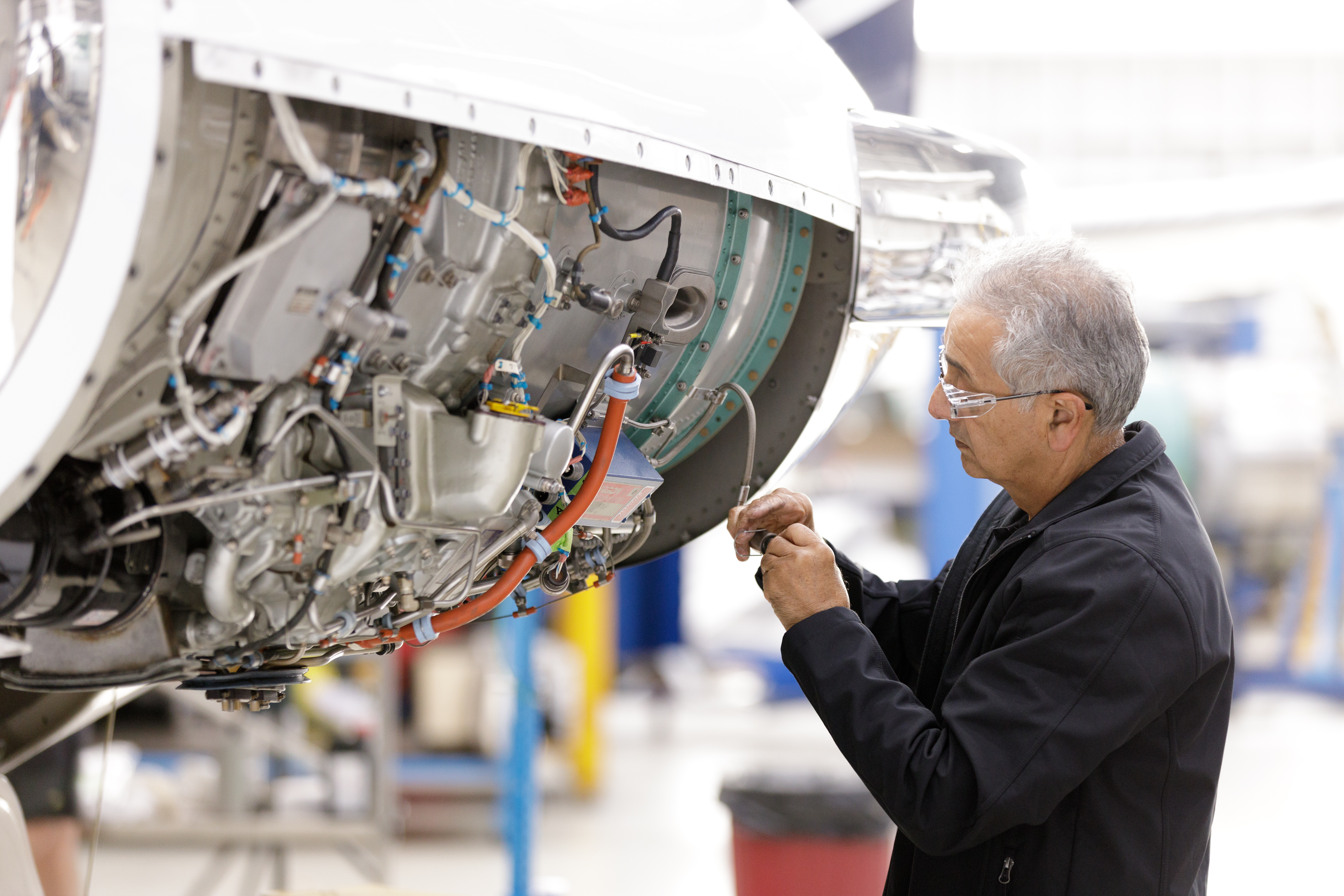 Aircraft engine maintenance with technician adjusting components inside a hangar